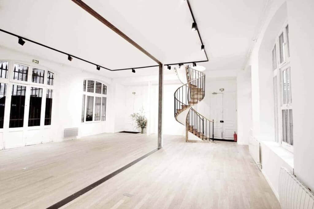 White gallery with light parquet flooring, white walls and large windows