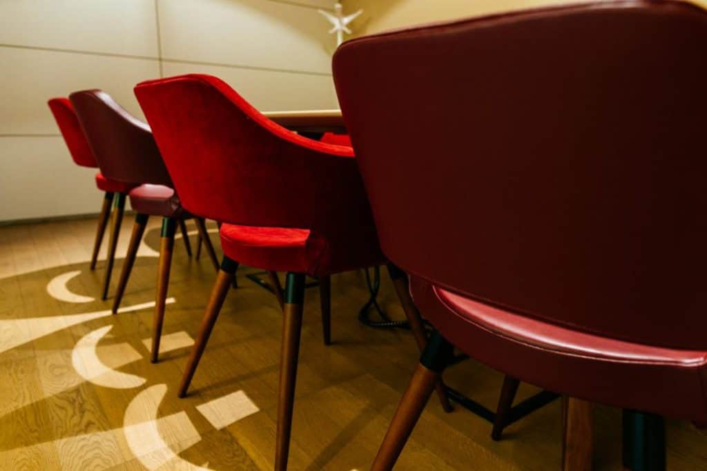 Sleek meeting room with glass walls featuring wooden floors and red curtains.