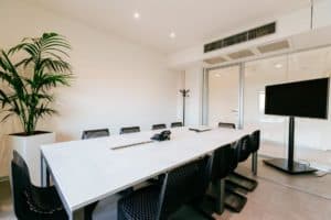 White boardroom with a lively atmosphere featuring a modern design, a white conference table and black chairs.