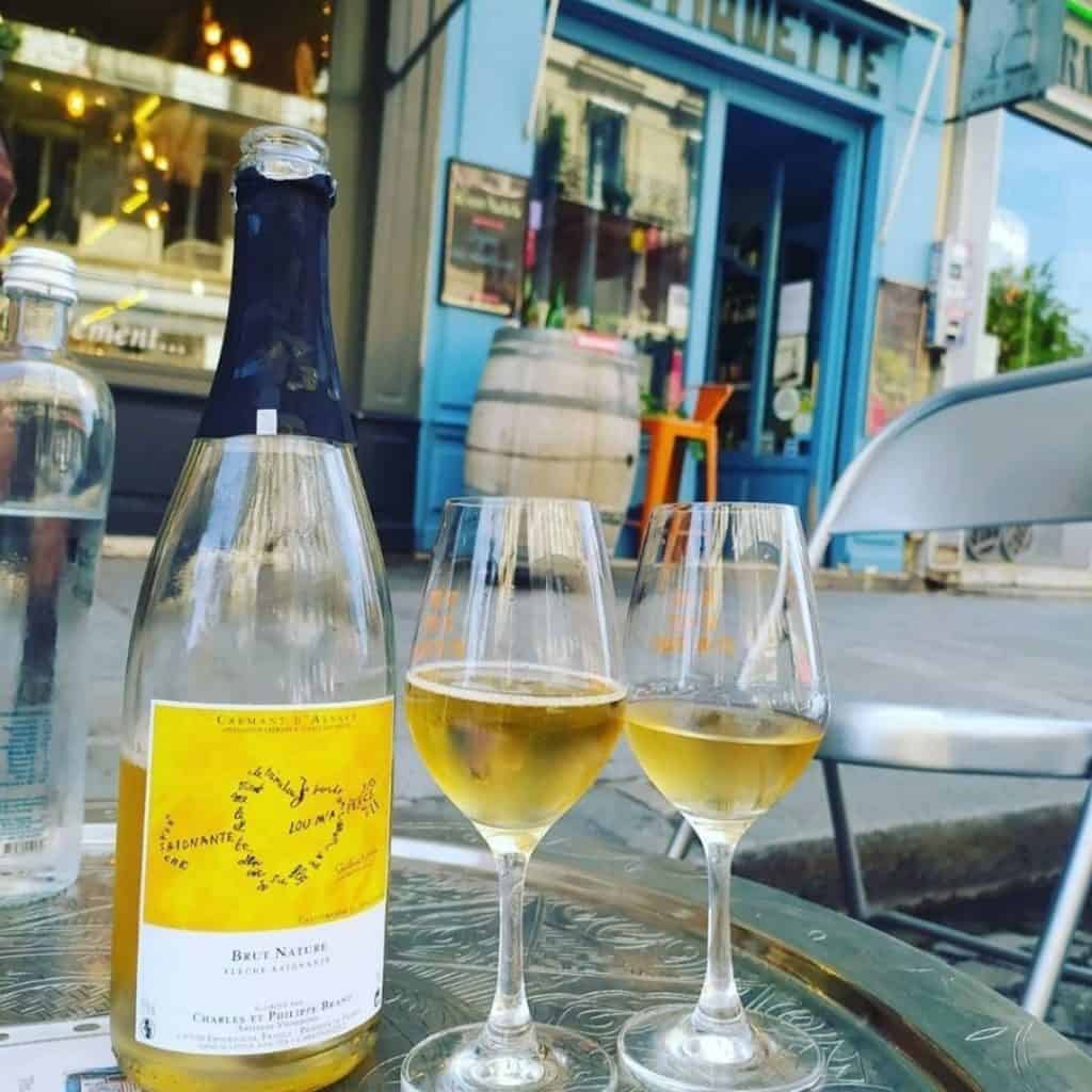 Two white wines and a bottle in front of a wine shop