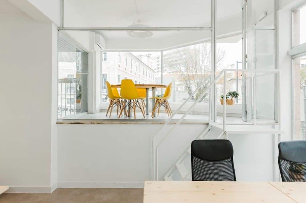 White seminar room in Lisbon with glass walls and yellow accent chairs
