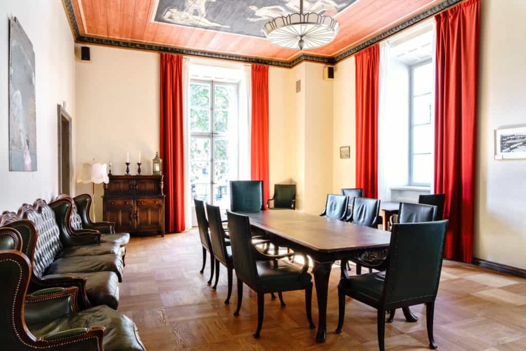 Classic meeting room with high ceiling, parquet flooring and retro leather chairs