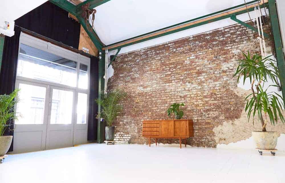 Rustic studio with a modern twist. Former workshop, still showing brick wall. White walls and ceiling, space for make-up and showering.
